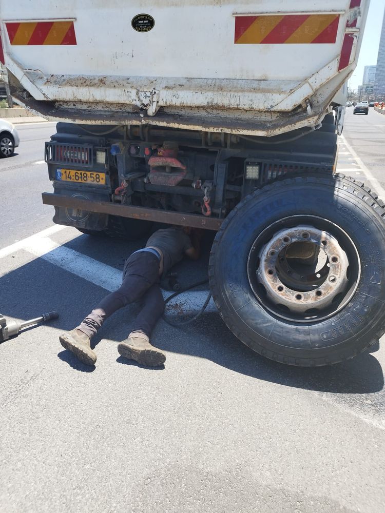 עבודה מתחת למשאית רכינה לשחרור הגלגל
