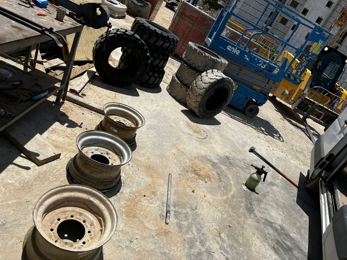 עמדת עבודה זמנית באתר בנייה: חישוקים, צמיגי מלגזה וצמיגי שטח בתהליך החלפה.