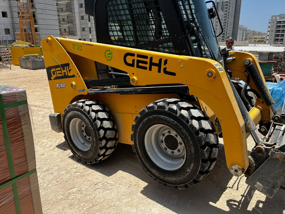 אותו מעמיס GEHL R260 עם ארבעה צמיגים חדשים, מוכן לעבודה באתר הבנייה.