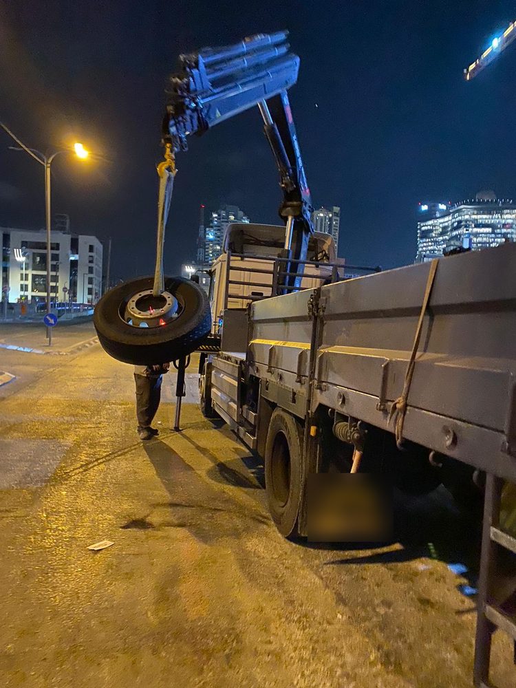 גלגל של משאית מנוף מורד בעזרת המנוף בזמן החלפת גלגל בלילה במודיעין