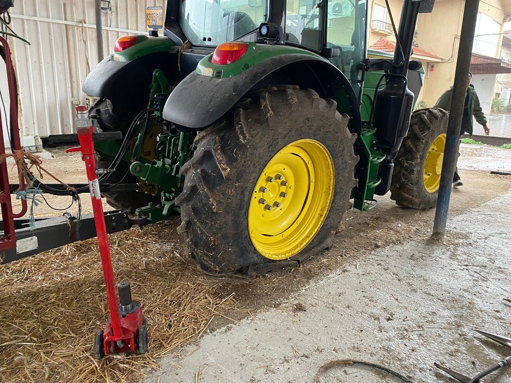 טרקטור John Deere מורם על ג'ק הידראולי ותומכת, לפני פירוק הגלגל האחורי