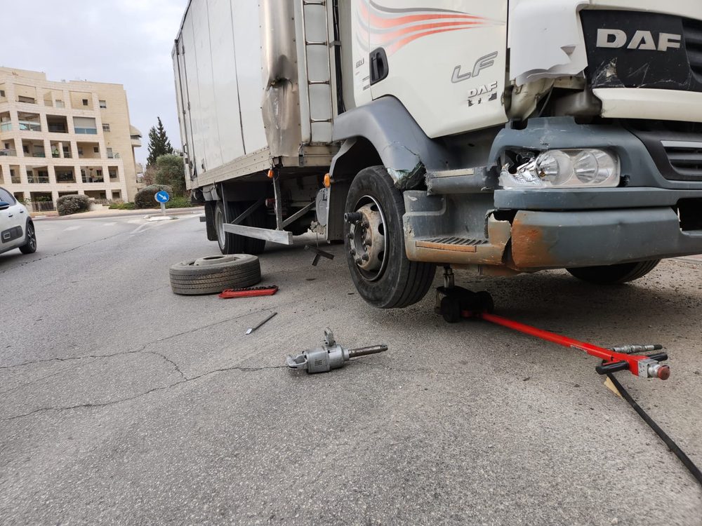 משאית DAF מורמת על ג'ק בזמן החלפת גלגל קדמי ברחוב בראשון לציון